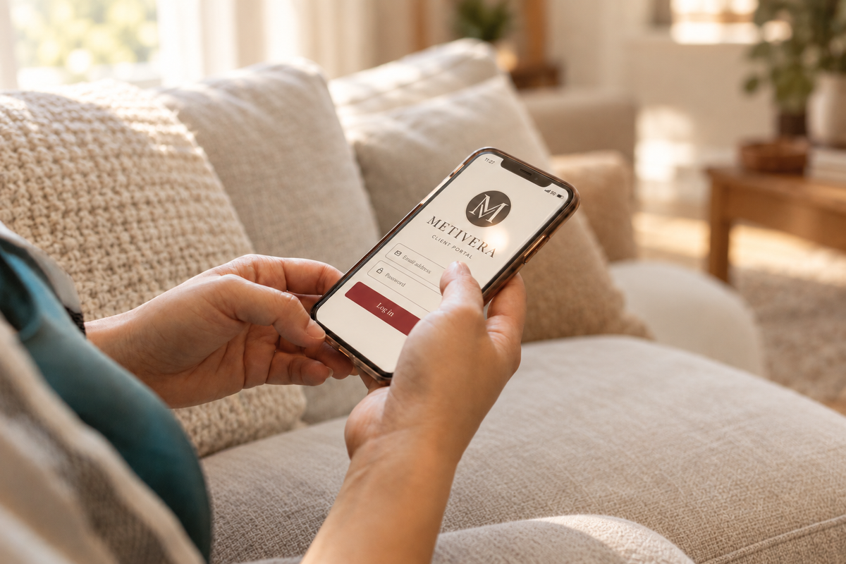 A person relaxing on a cream couch with the METIVERA client portal open on their phone.