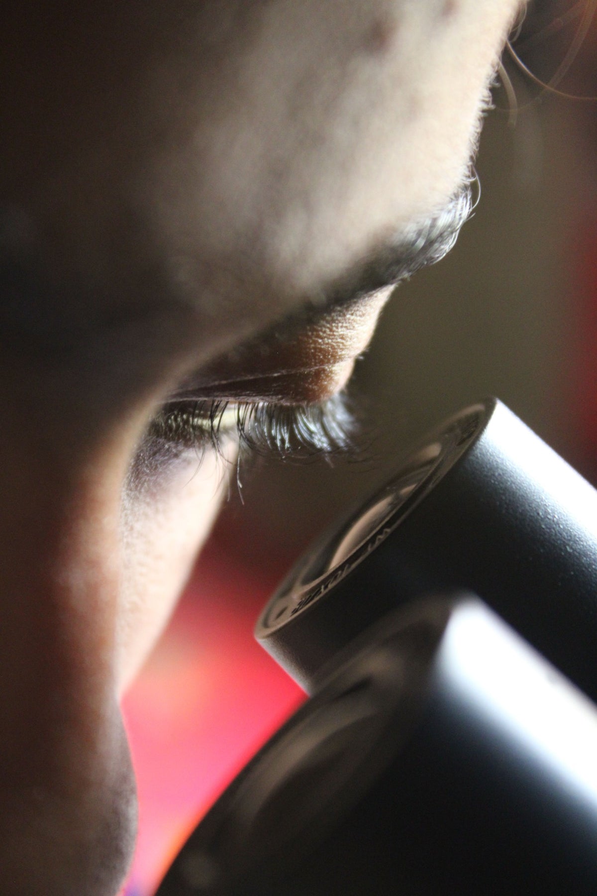 Close-up of a person examining through a microscope