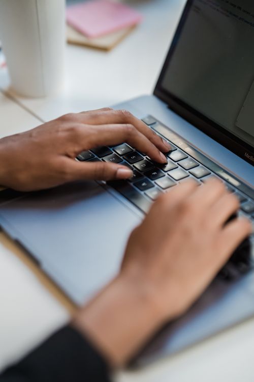 Close-up of hands typing on a laptop keyboard